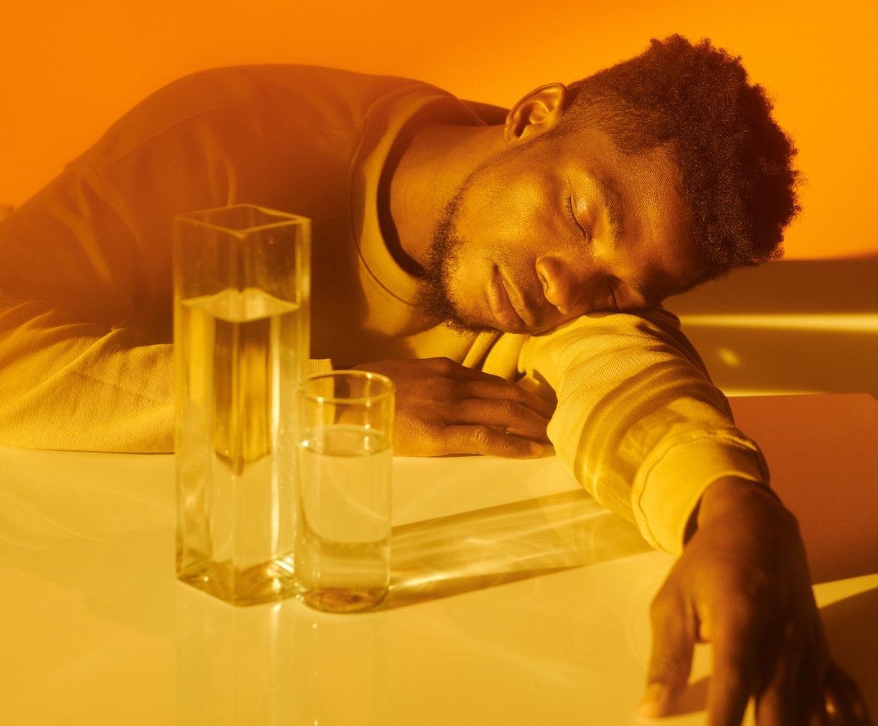 Young black man is sleeping on the table in dark room.