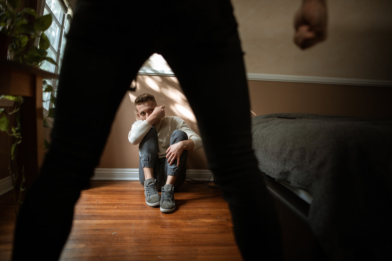 Scared kid from other person is seating on the floor.