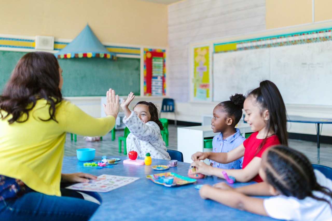 Young female teacher is playing with young kids at school.