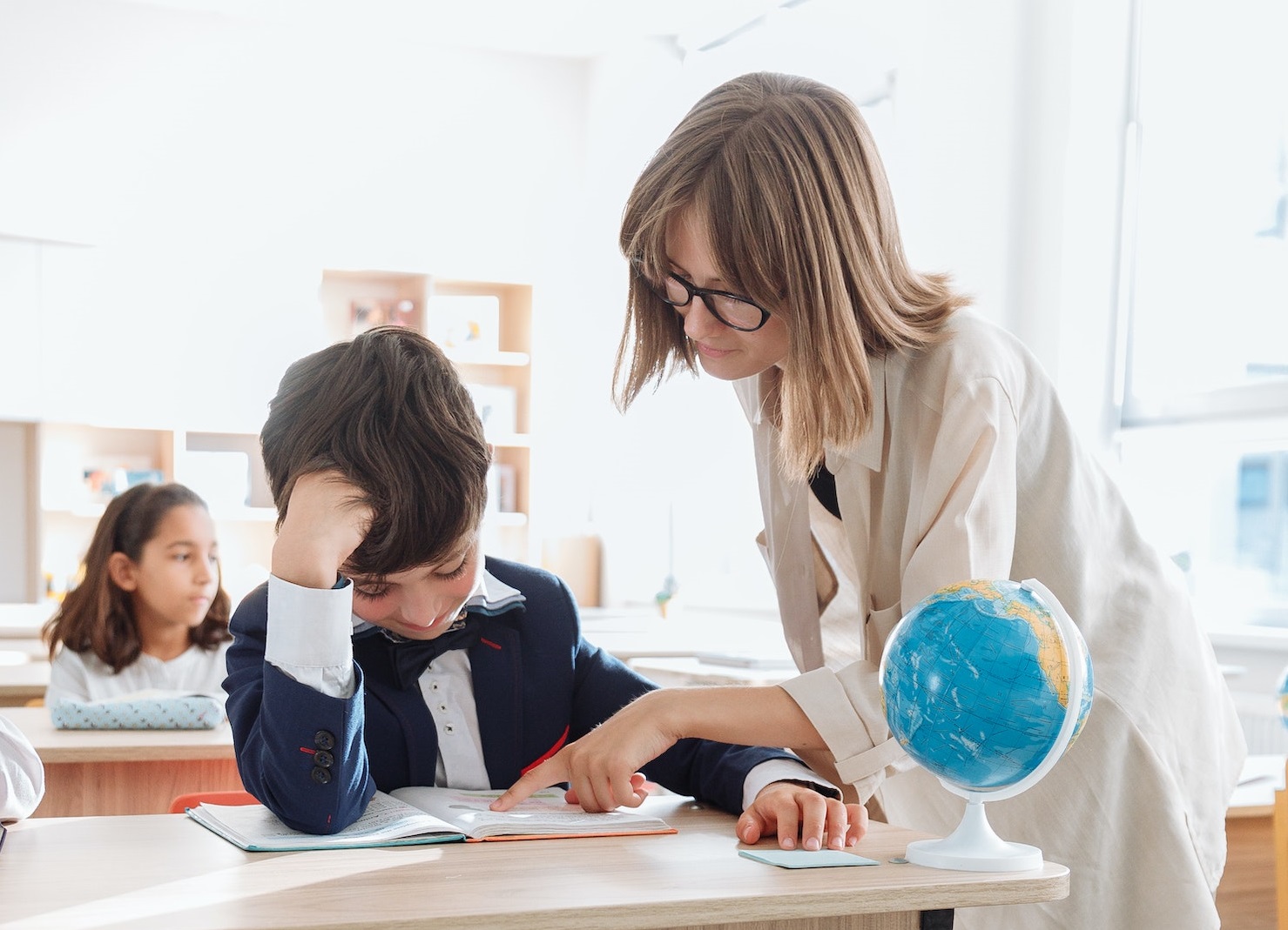 Female teacher is talking with a young student at class.