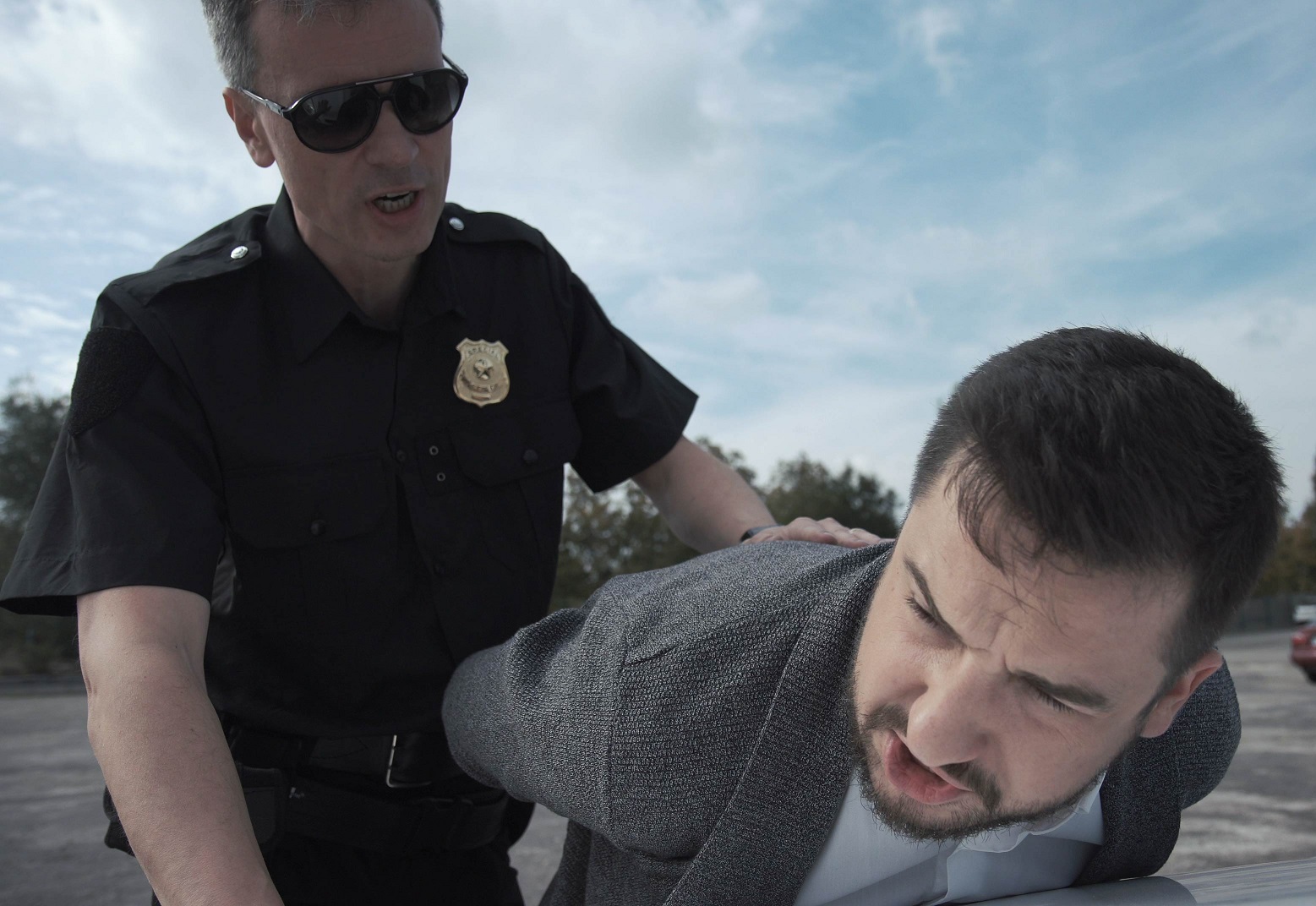 Police officer arresting criminal outside.