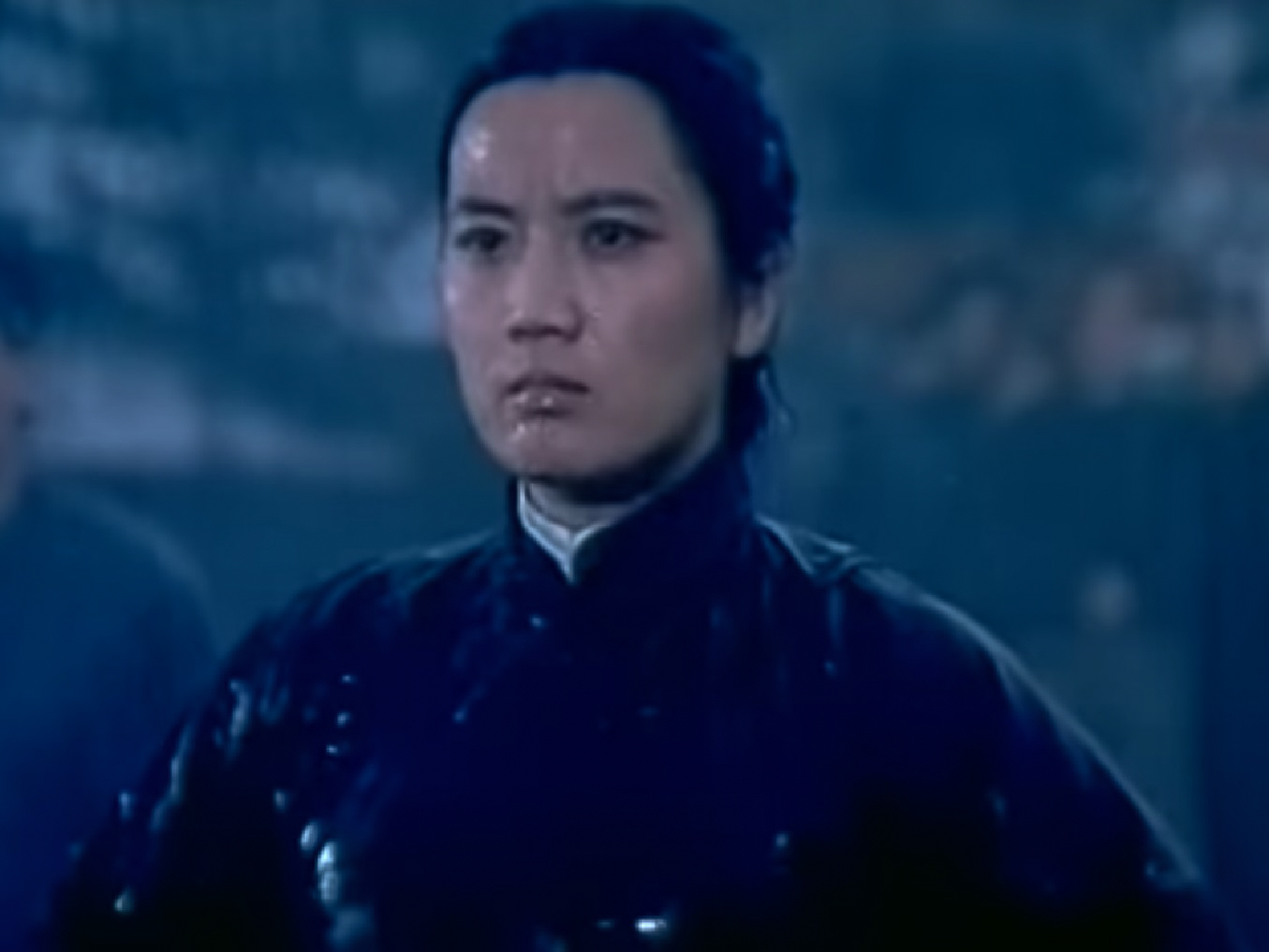 Screenshot: Qiu Jin (Xiuming Li) is standing outside in the rain with angry face - from Qiu Jin (1983)
