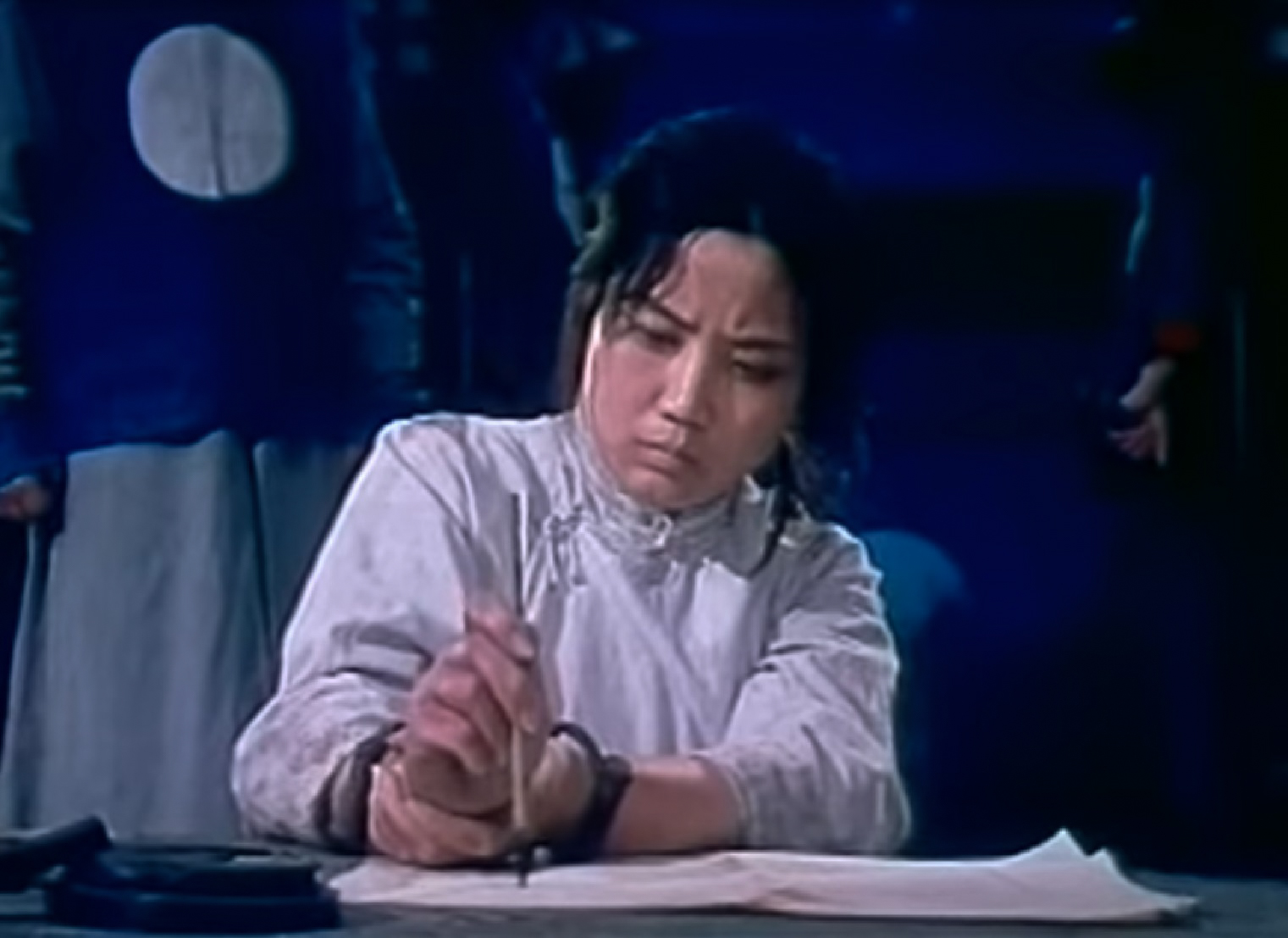 Screenshot: Qiu Jin (Xiuming Li) wearing handcuffs is writing a letter - from Qiu Jin (1983)