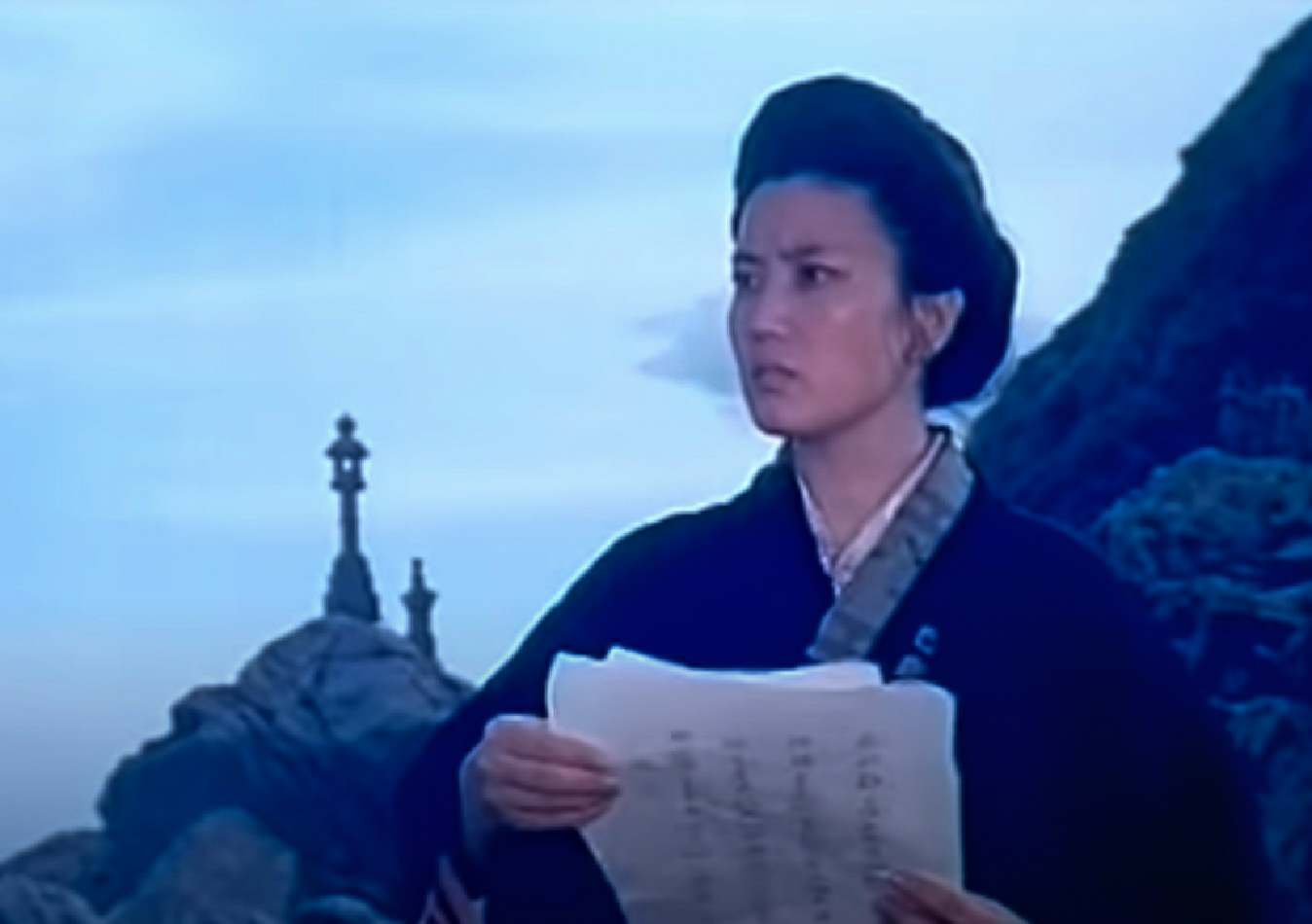 Screenshot: Qiu Jin (Xiuming Li) is holding a poem in her hand ,looking outside - from Qiu Jin (1983)