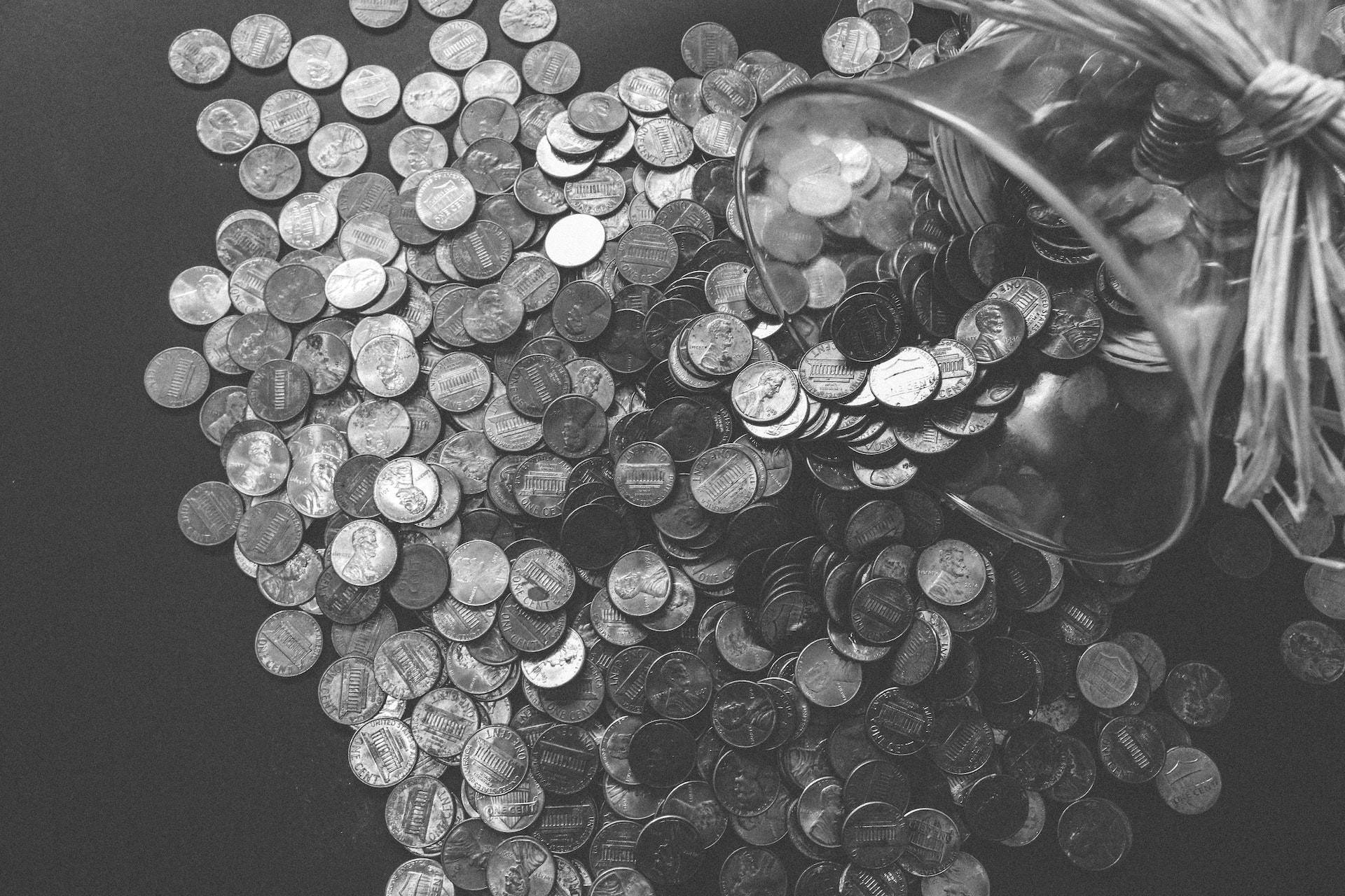 Grayscale Photo of Coins coming out of a glass bottle