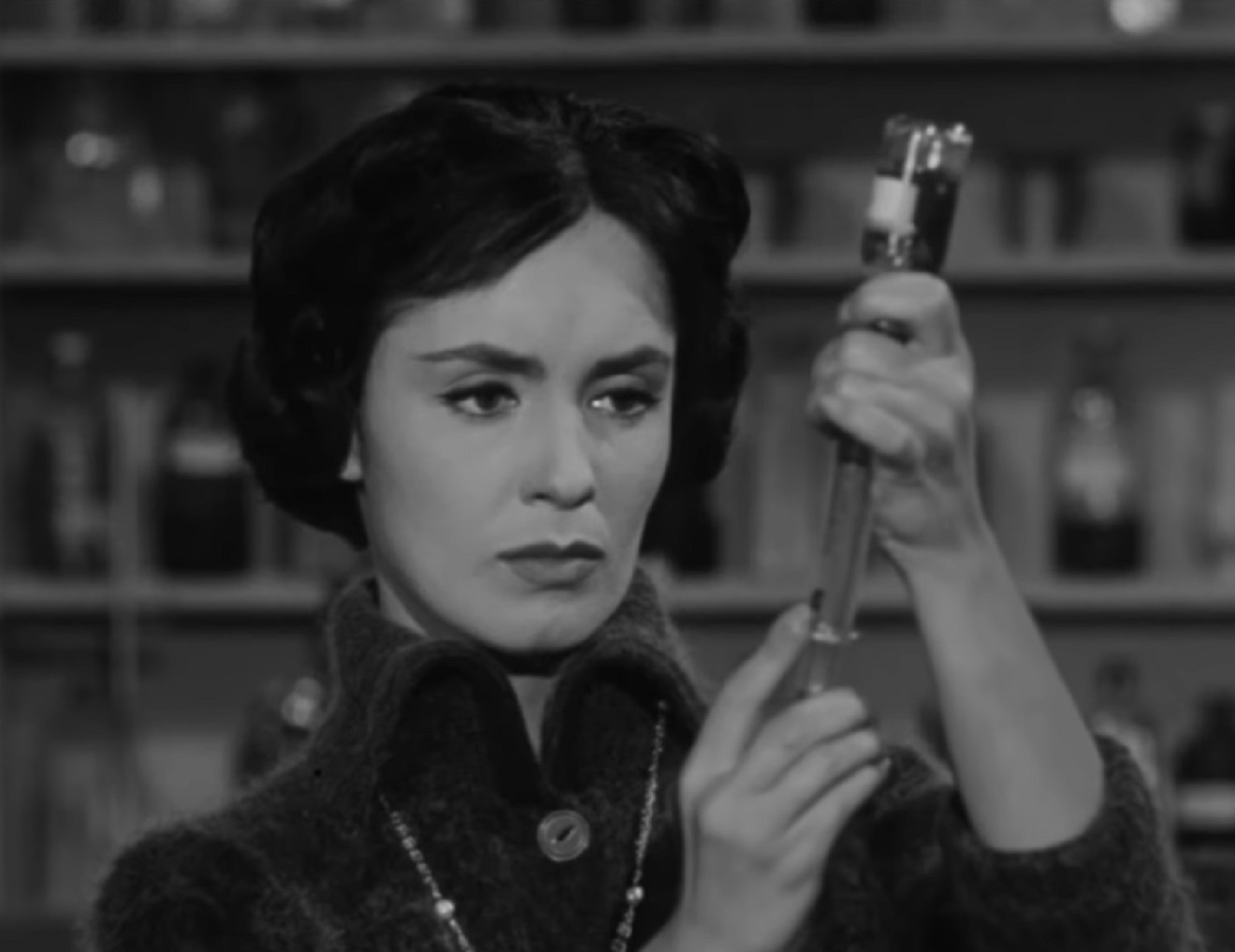 Screenshot: Susan Cabot is holding a syringe in hands- from The Wasp Woman (1959).