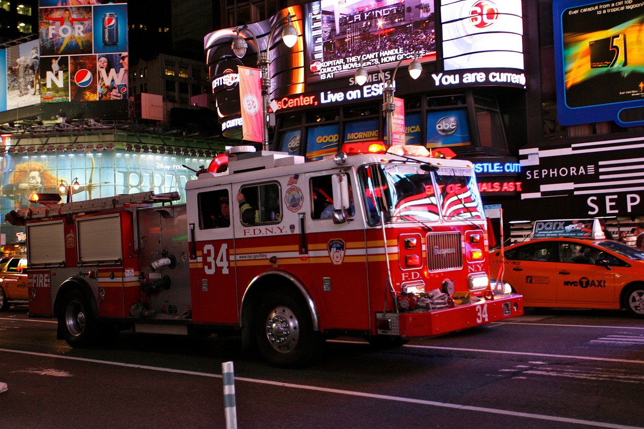 Photo of a Fire truck driving on a City Street surrounded by buildings