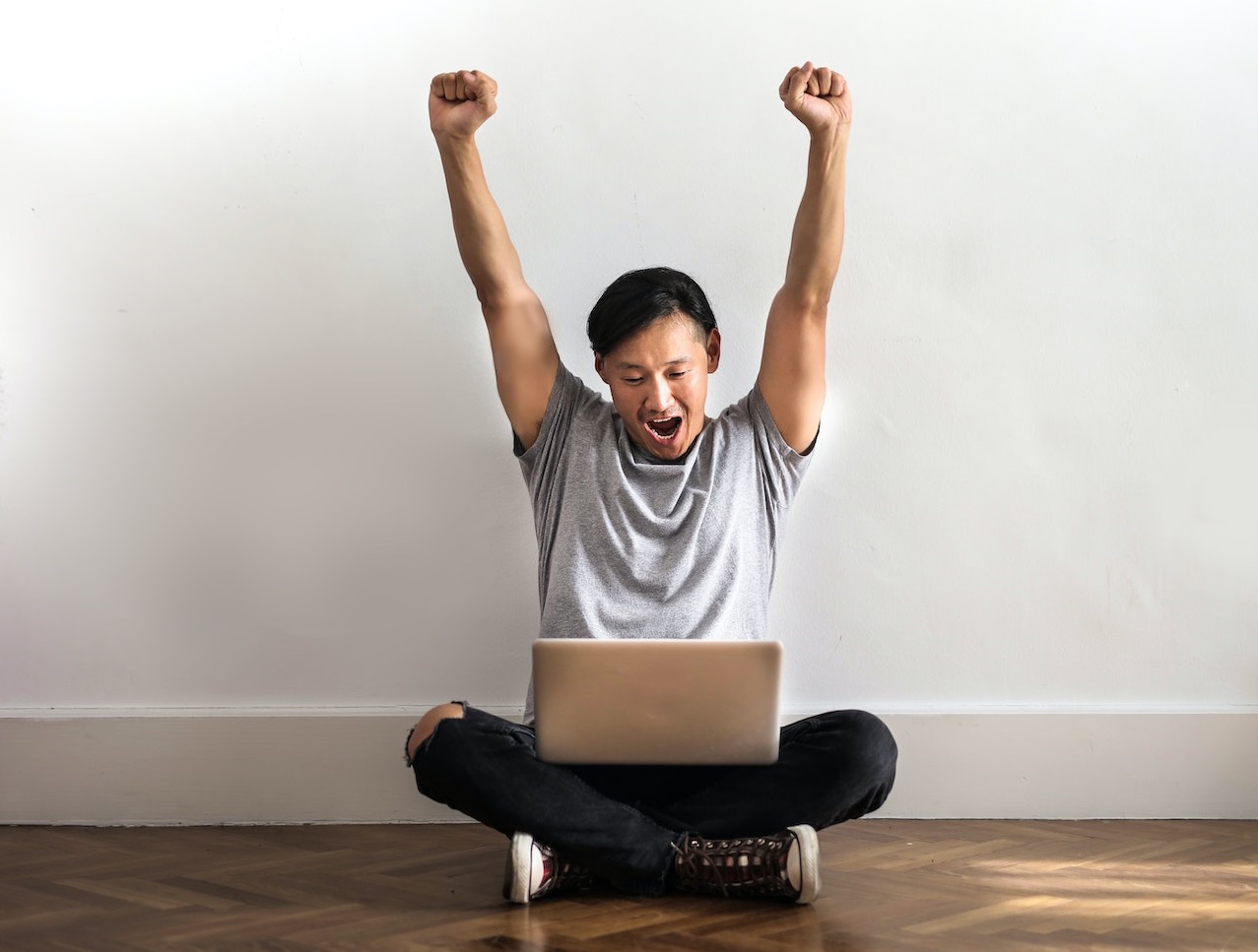Young man is seating on the floor ,looking at laptop.
