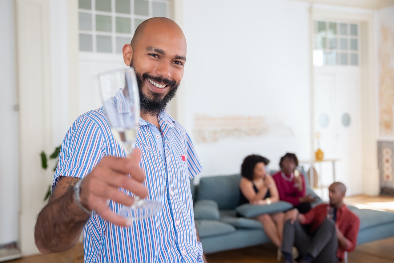 Man in shirt is holding a wine glass and smiling at party.