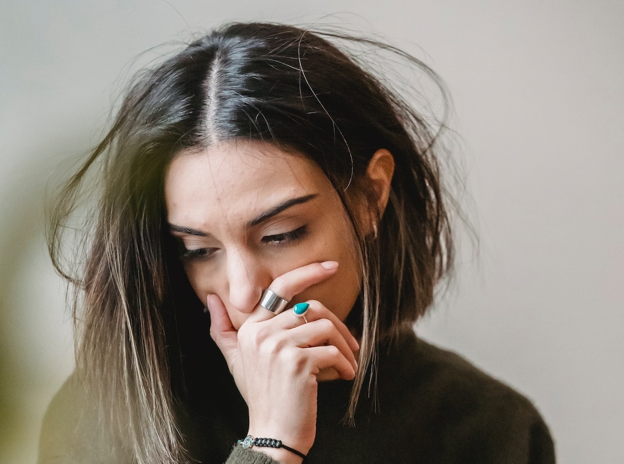 Young woman is looking down with sad face.