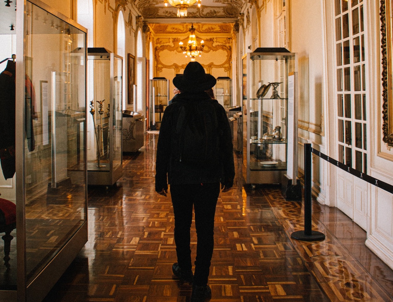 Man wearing black hat is walking at museum hallway.