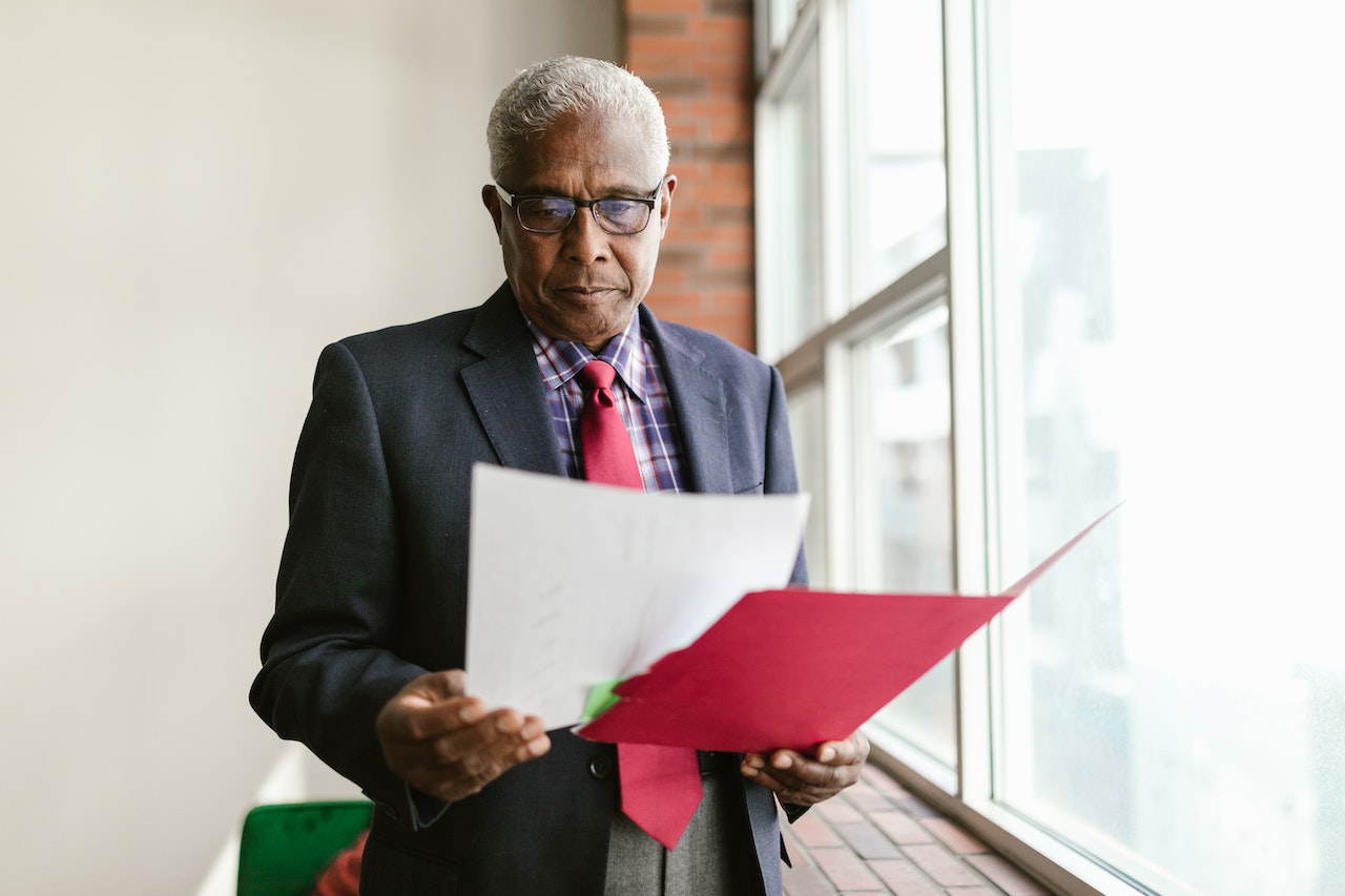 Senior man is holding and reading a documents at hallway.