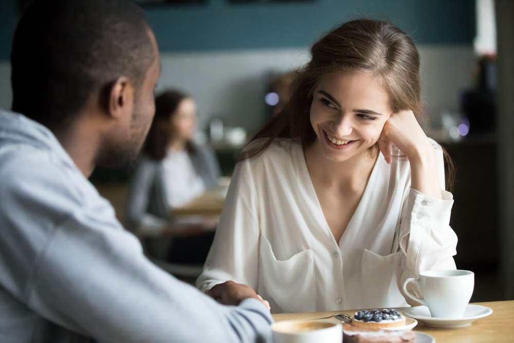 Woman in white shirt laughing sitting in a café at a date