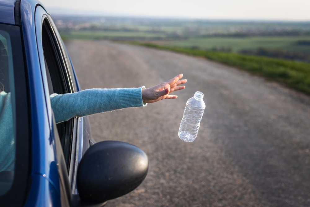 Driver throwing away plastic bottle from car window
