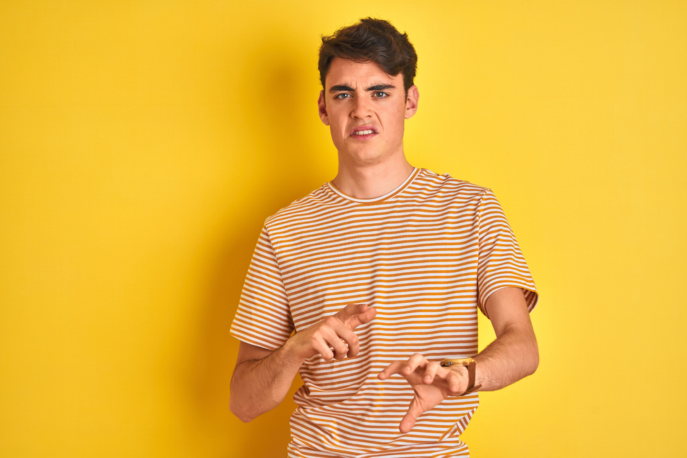 Teenager boy wearing yellow t-shirt with disgusted expression