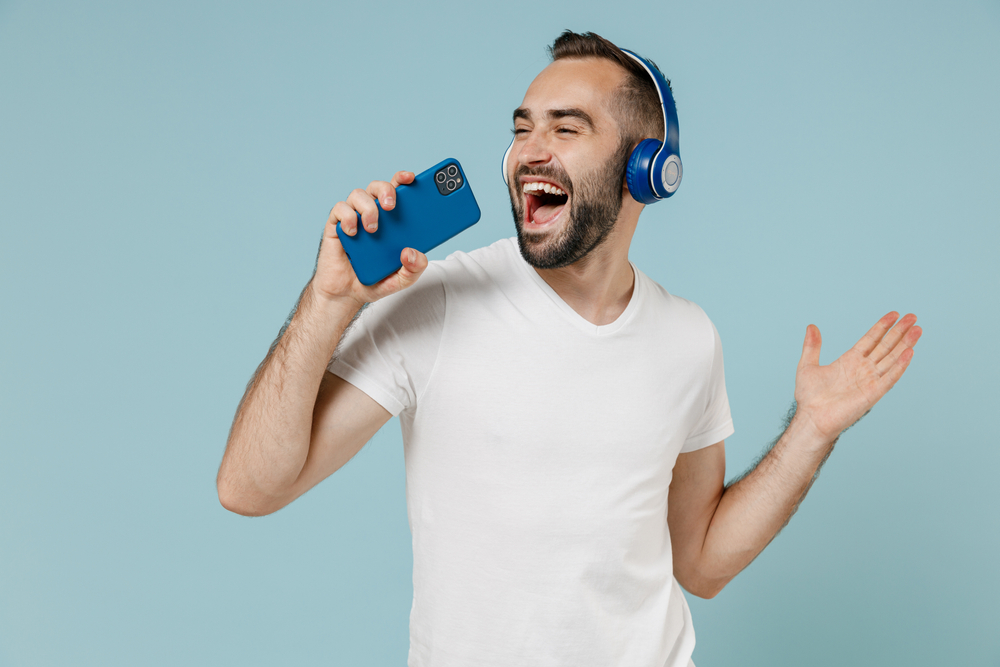 Young man wearing   headphones listening  to music  and singing