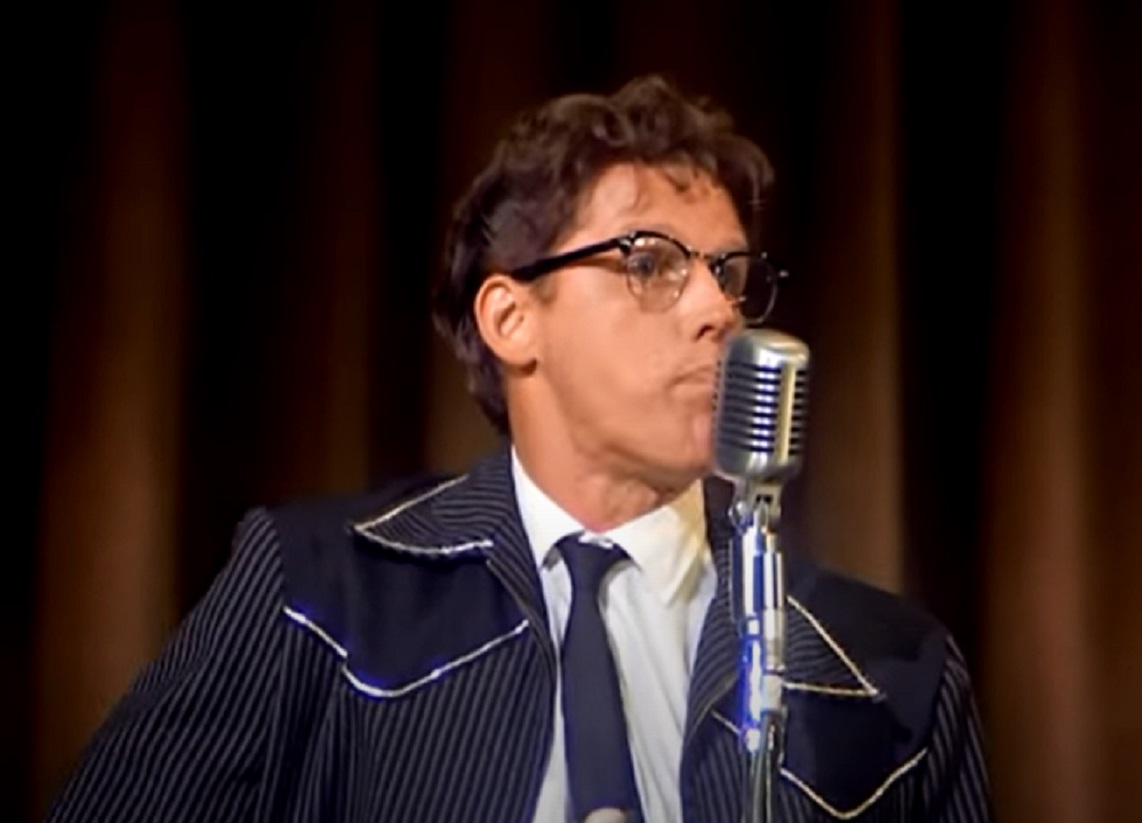Screenshot: Buddy Holly wearing blue suit is performing live on stage - from The Buddy Holly Story (1978)