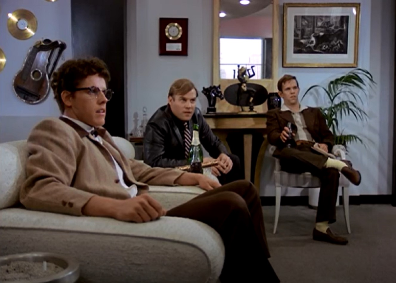 Screenshot: Buddy Holly is seating in room with his band - from The Buddy Holly Story (1978).