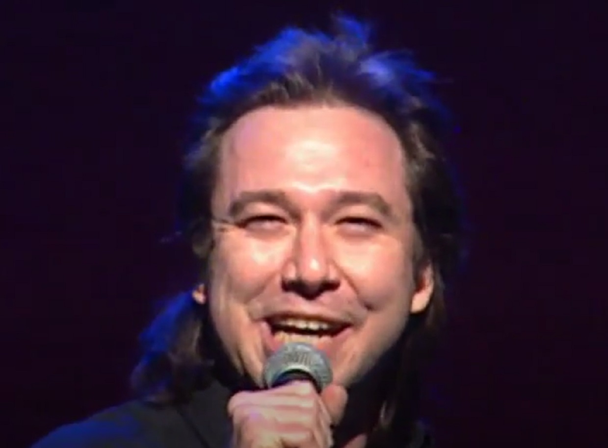 Screenshot: Bill Hicks is performing live and smiling - from American- The Bill Hicks Story (2009).