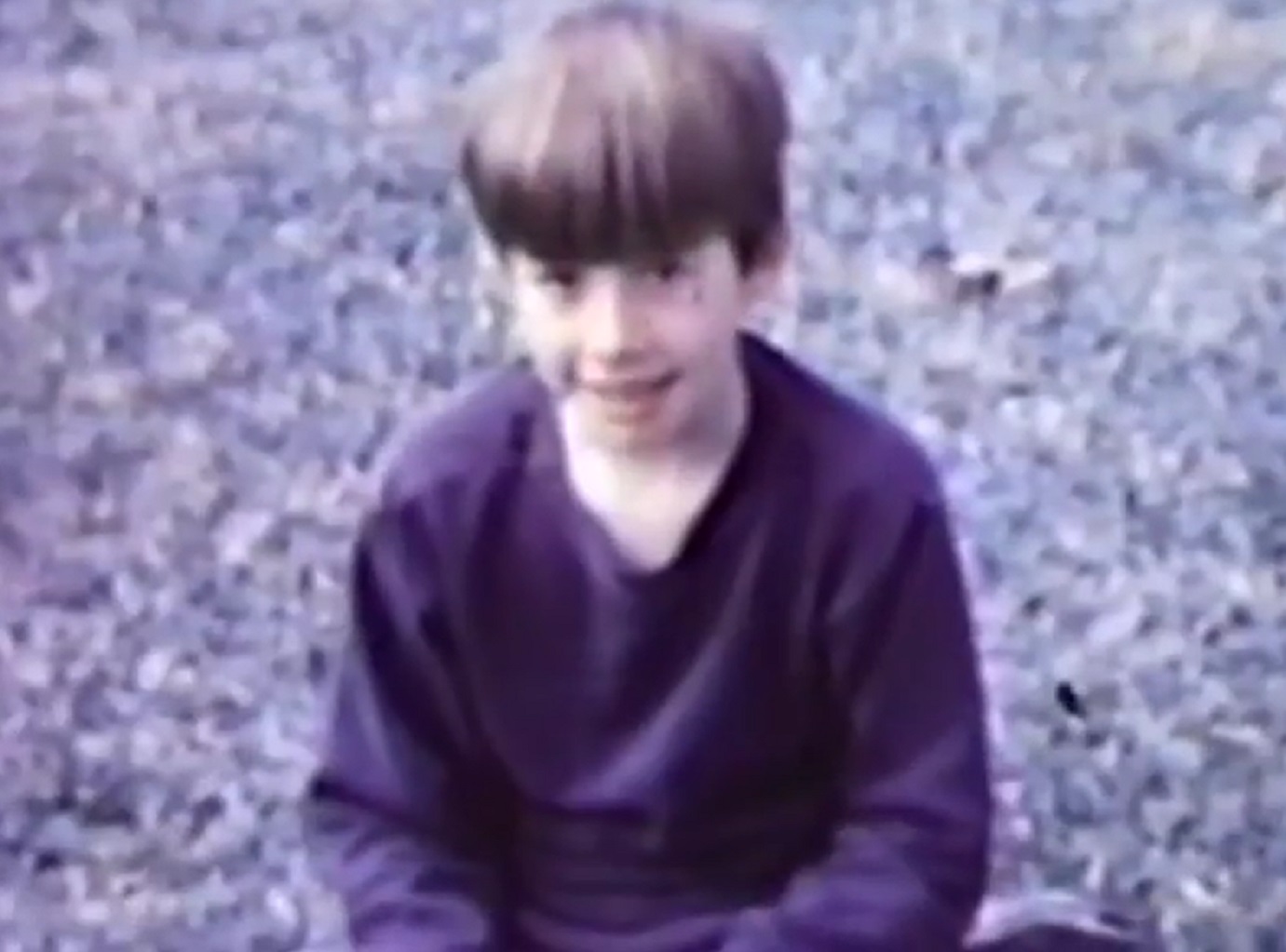 Screenshot: Bill Hicks ,young is smiling and looking at camera - from American: The Bill Hicks Story (2009)