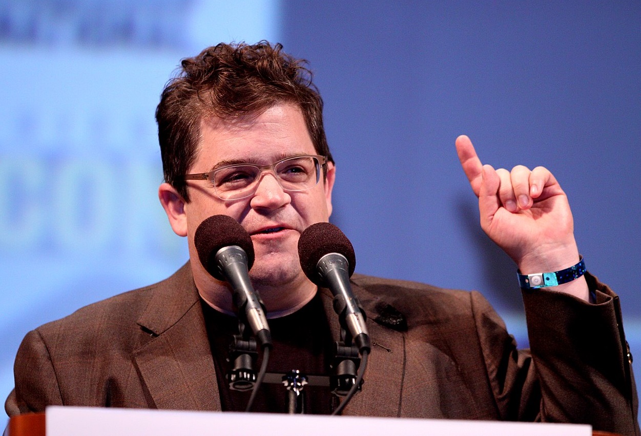 Patton Oswalt wearing brown jacket is holding a speech - 2010