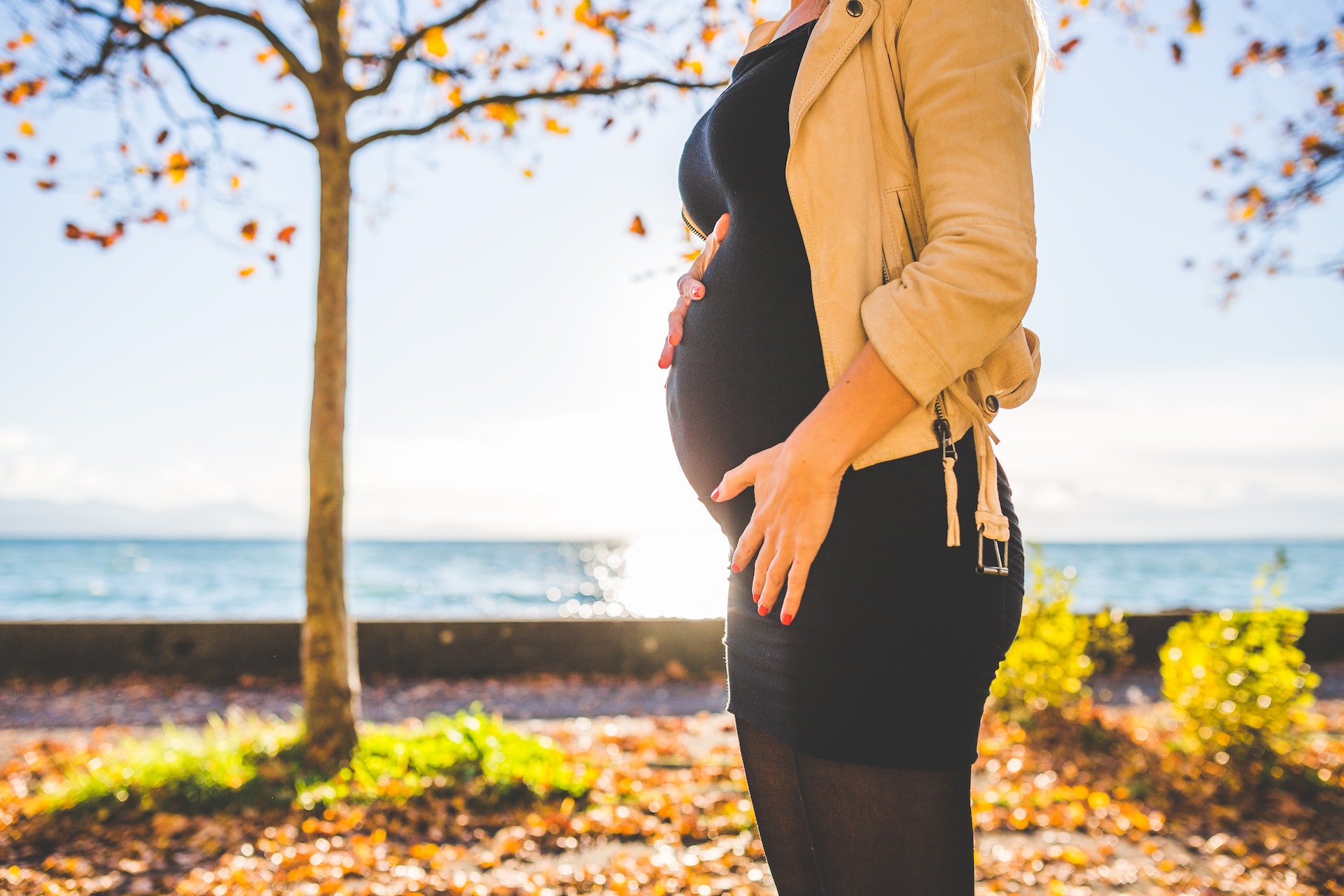 Pregnant Woman Wearing Beige Long Sleeve Shirt Standing Near Brown Tree