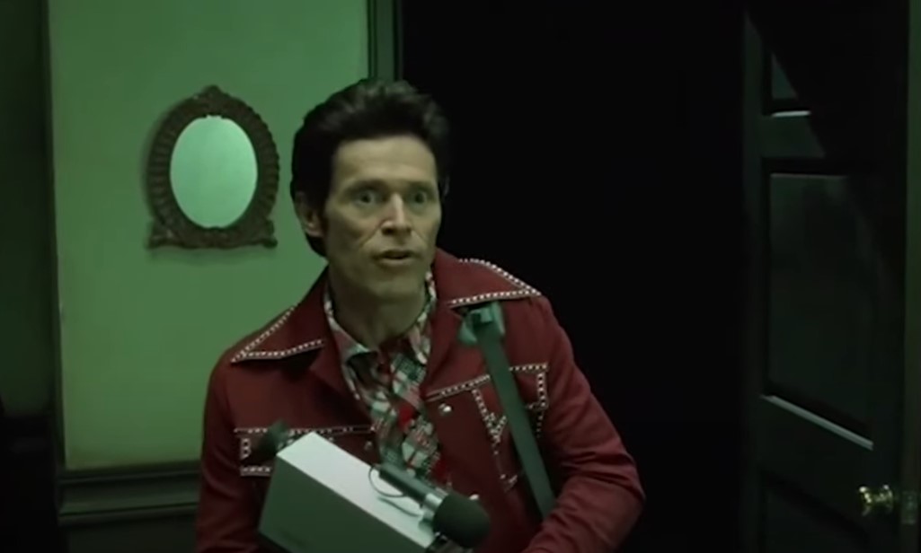 Willem Dafoe  as John Carpenter in red jacket leaving