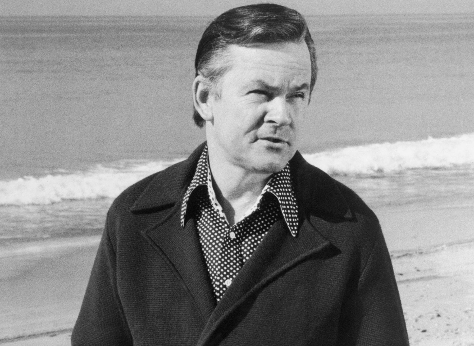 Portrait of Bob Crane in coat at the beach