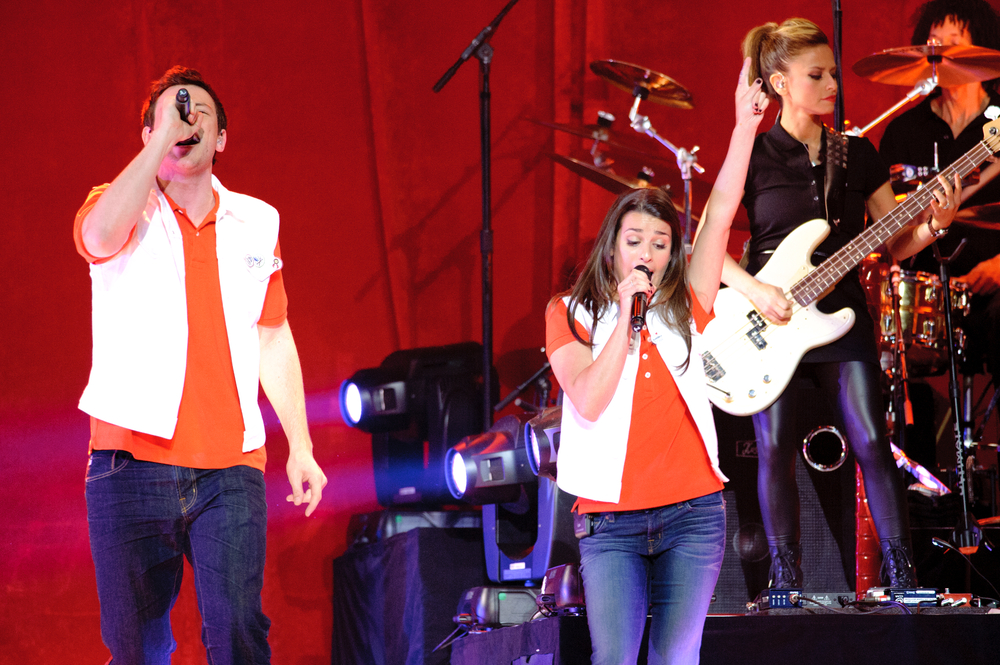 Corey Monteith and Lea Michelle perform  in orange t-shirts and jeans with live band