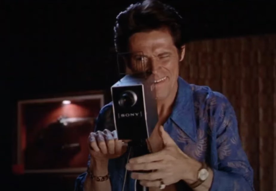 Willem Dafoe  as John Carpenter in blue shirt