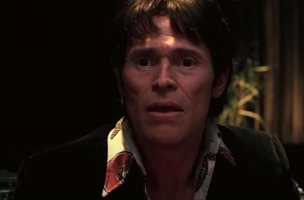 Willem Dafoe  as John Carpenter in black jacket