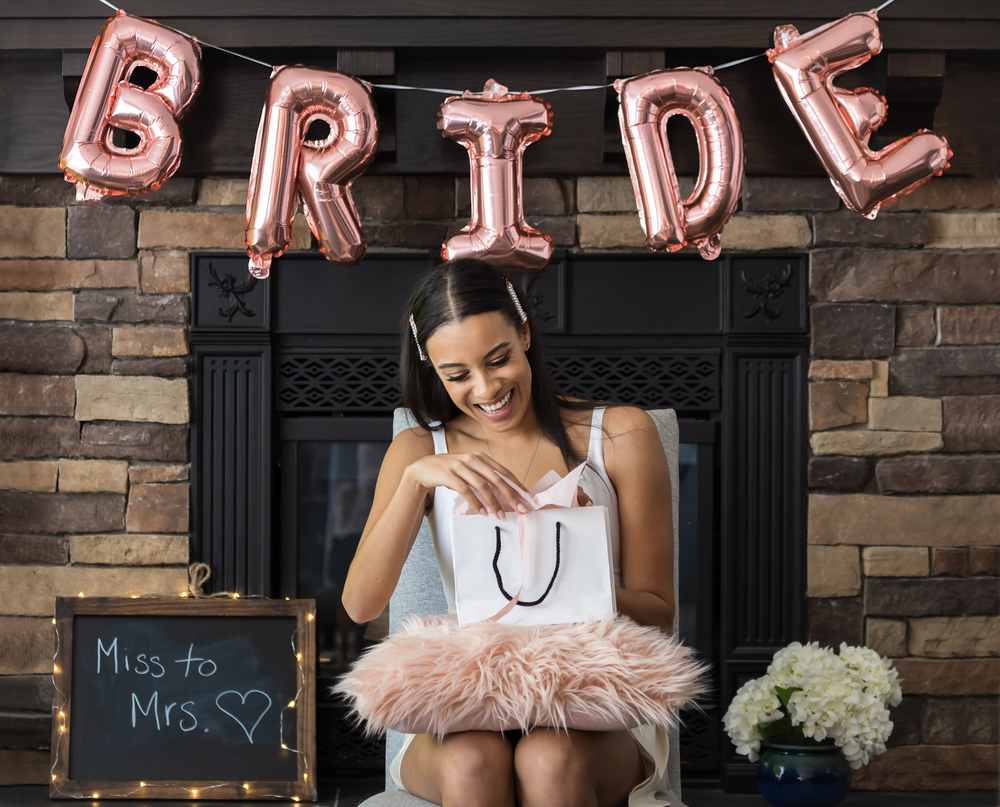 Young smiling African American woman opening a bridal shower present
