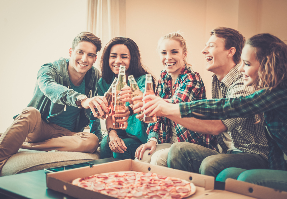 Group of young multi-ethnic friends with pizza and bottles of drink