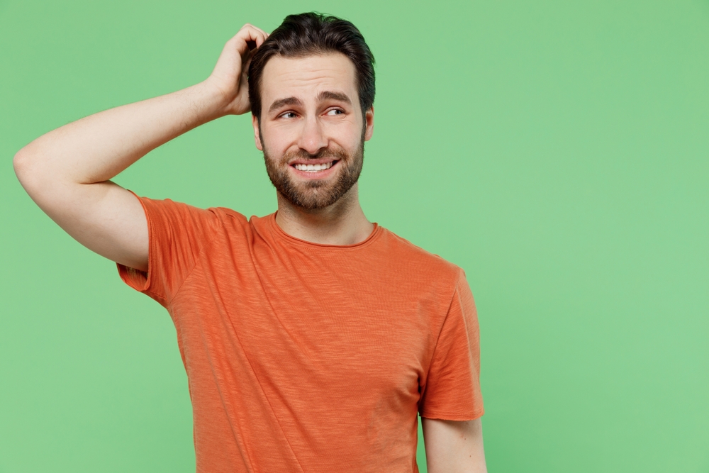 embarrassed man in orange t-shirt scratching his head