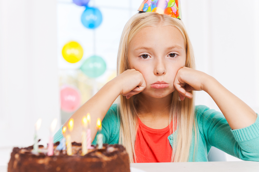 sad and lonely girl at her birthday in green sweater and party hat