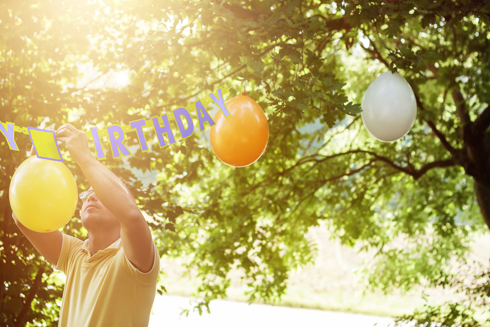 man hanging up balloons to prepare for the birthday party