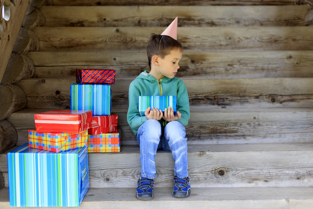 Sad boy at birthday sitting on stairs in green sweater