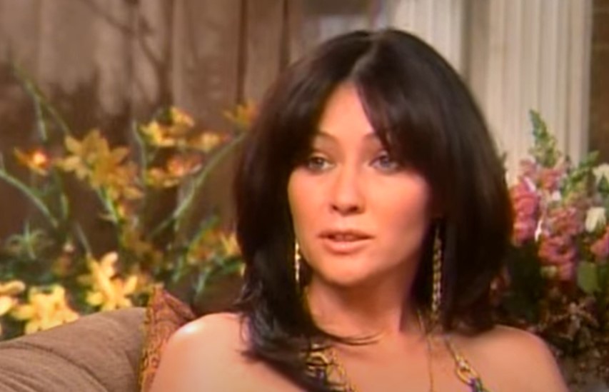shannen doherty sitting on a couch wearing earrings