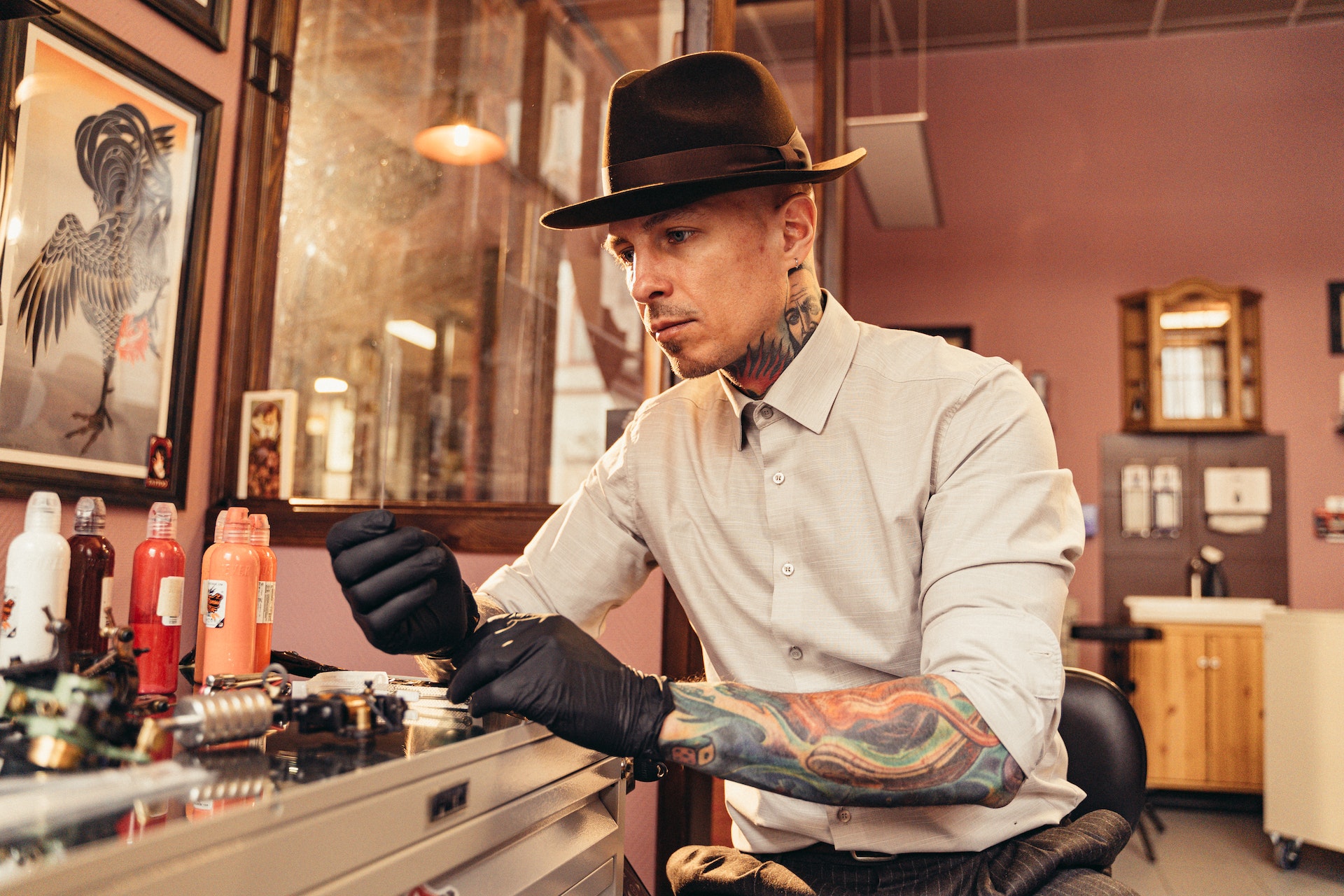 Tattoo artist in white shirt and hat preparing equipment to do a tattoo