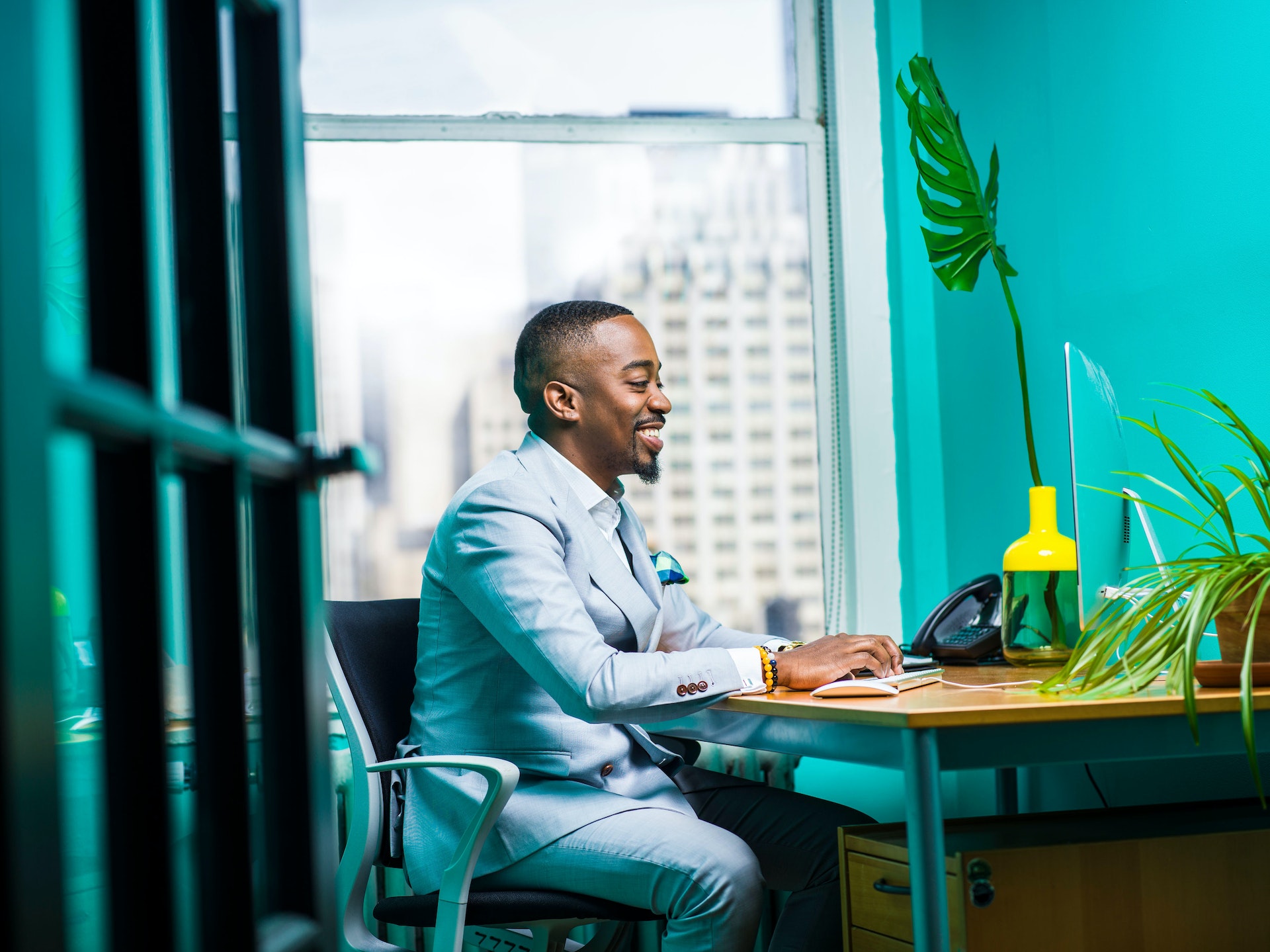 man in blue suit sitting at a desk in office working