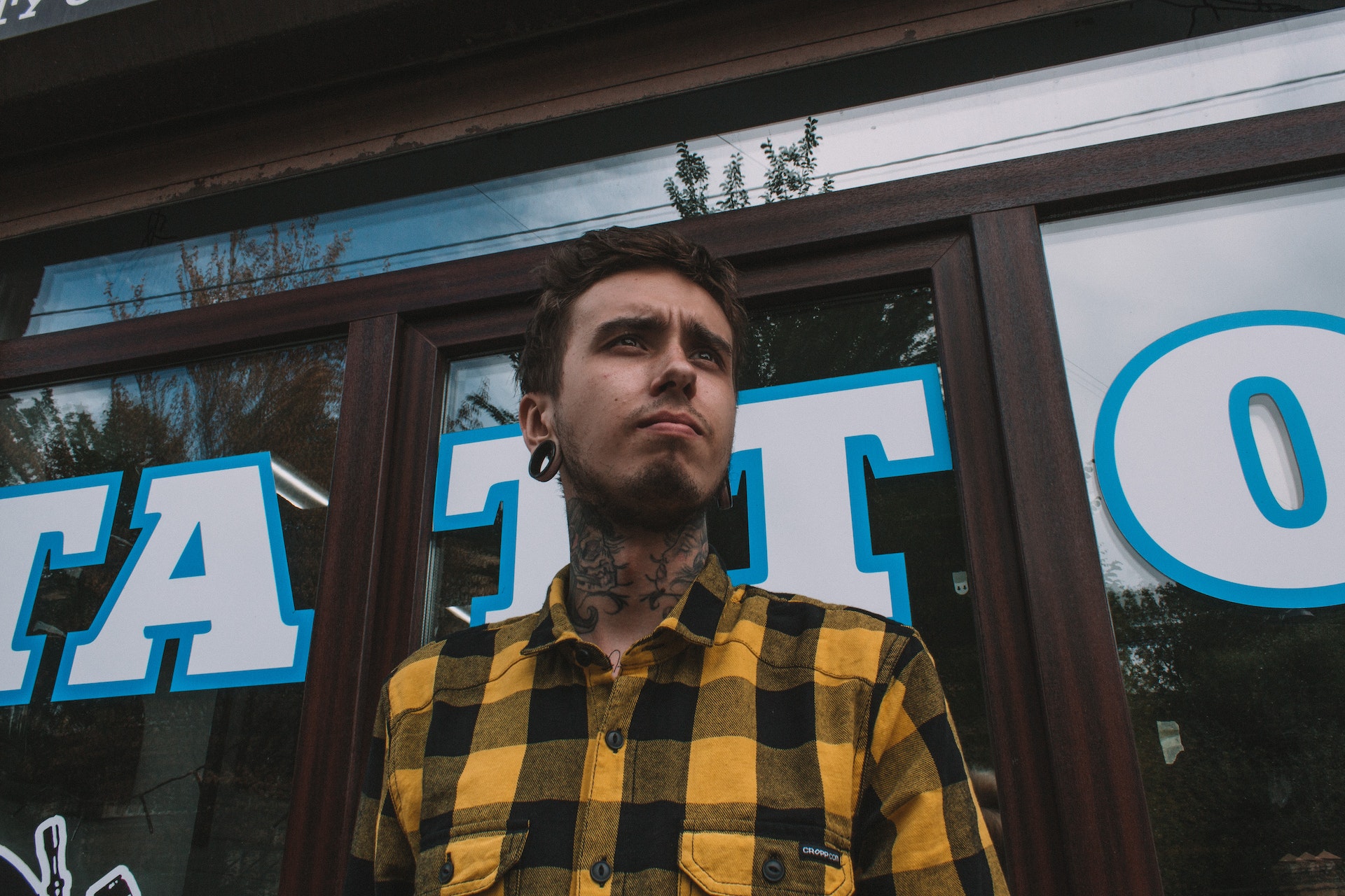 tattoo artist wearing black and yellow plaid shirt
