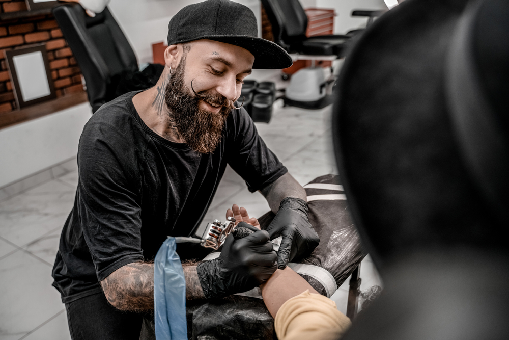 Male tattoo master in black t-shirt smiling tattooing