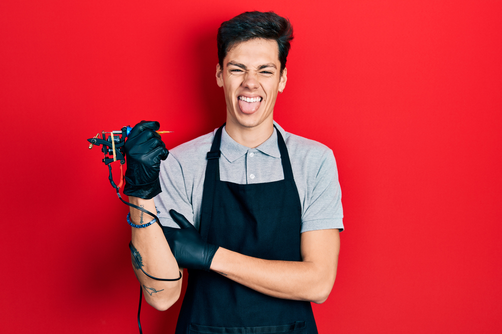 Young Hispanic man tattoo artist wearing professional uniform and gloves