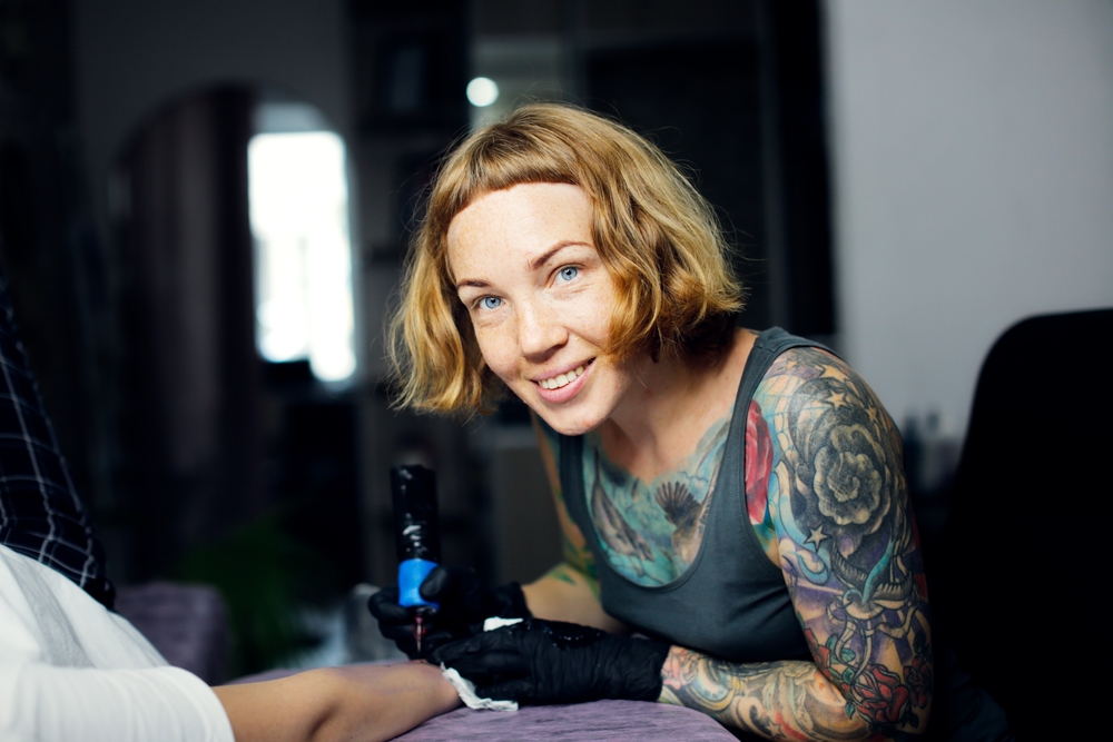 Female tattoo artist doing a tattoo on a client