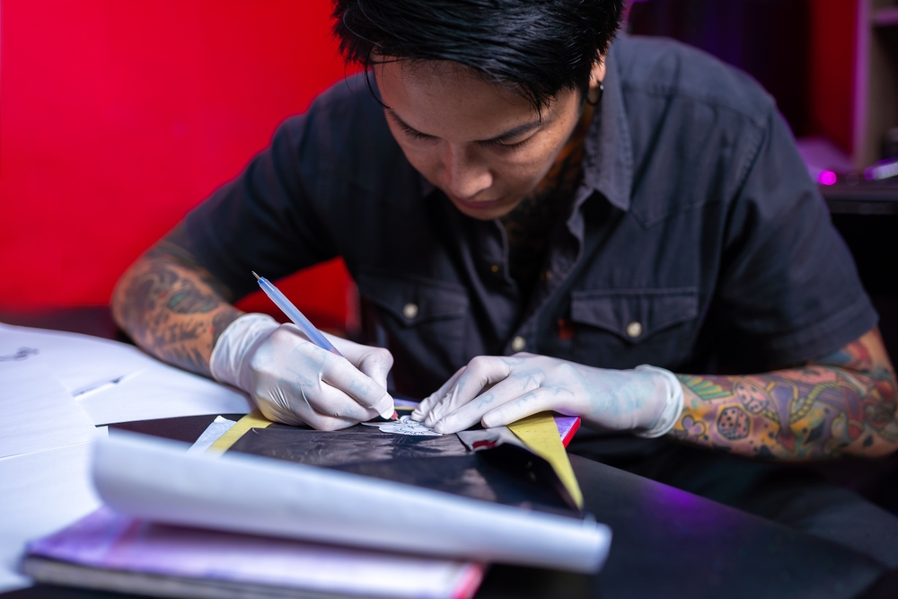Professional tattoo master man paints sketches