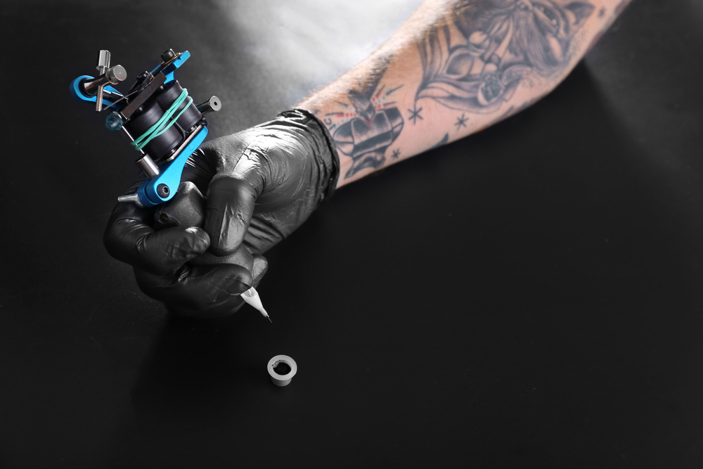 Tattooist hand in medical glove with tattoo machine