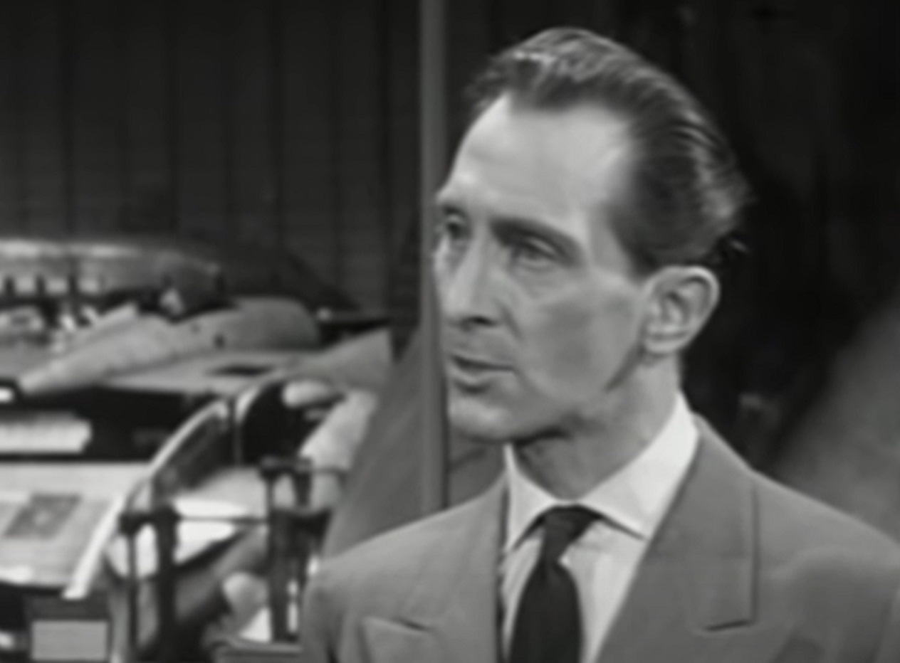 Screenshot of Peter Cushing in suit looking at side - from Cone of Silence (1960)