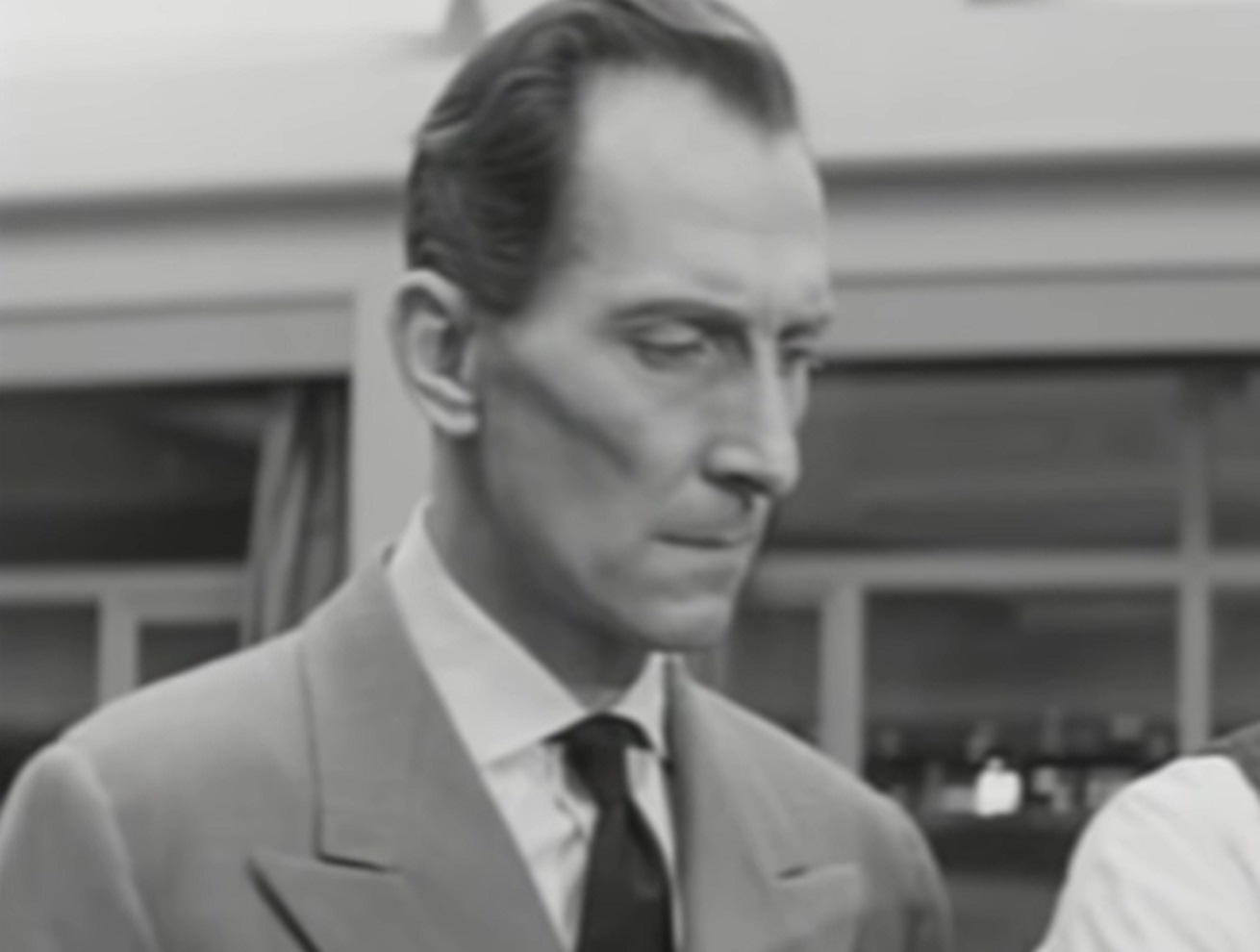Screenshot of Peter Cushing looking down upset - from Cone of Silence (1960)
