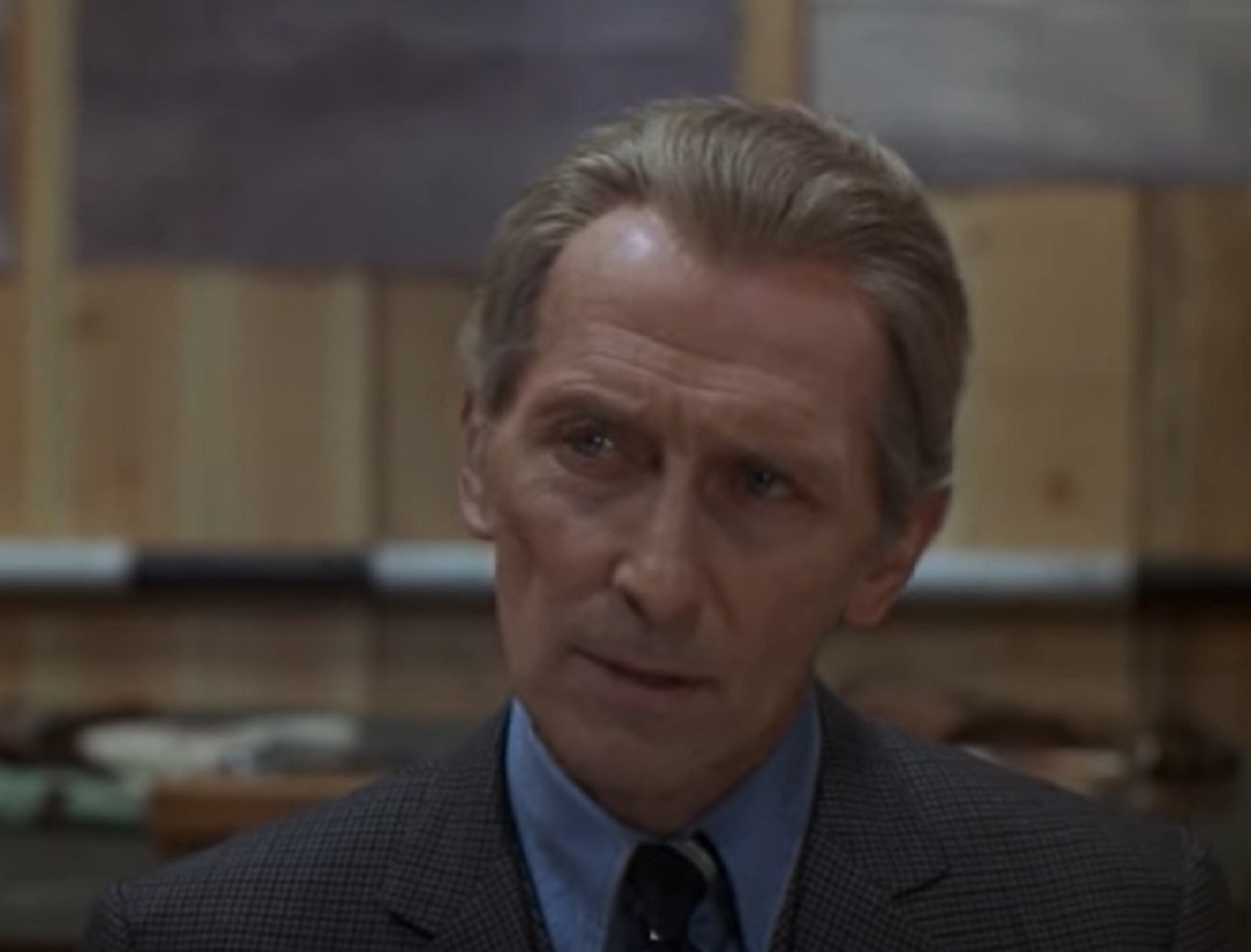 Screenshot of Peter Cushing seating in office and looking at side - from Nothing But the Night (1973)