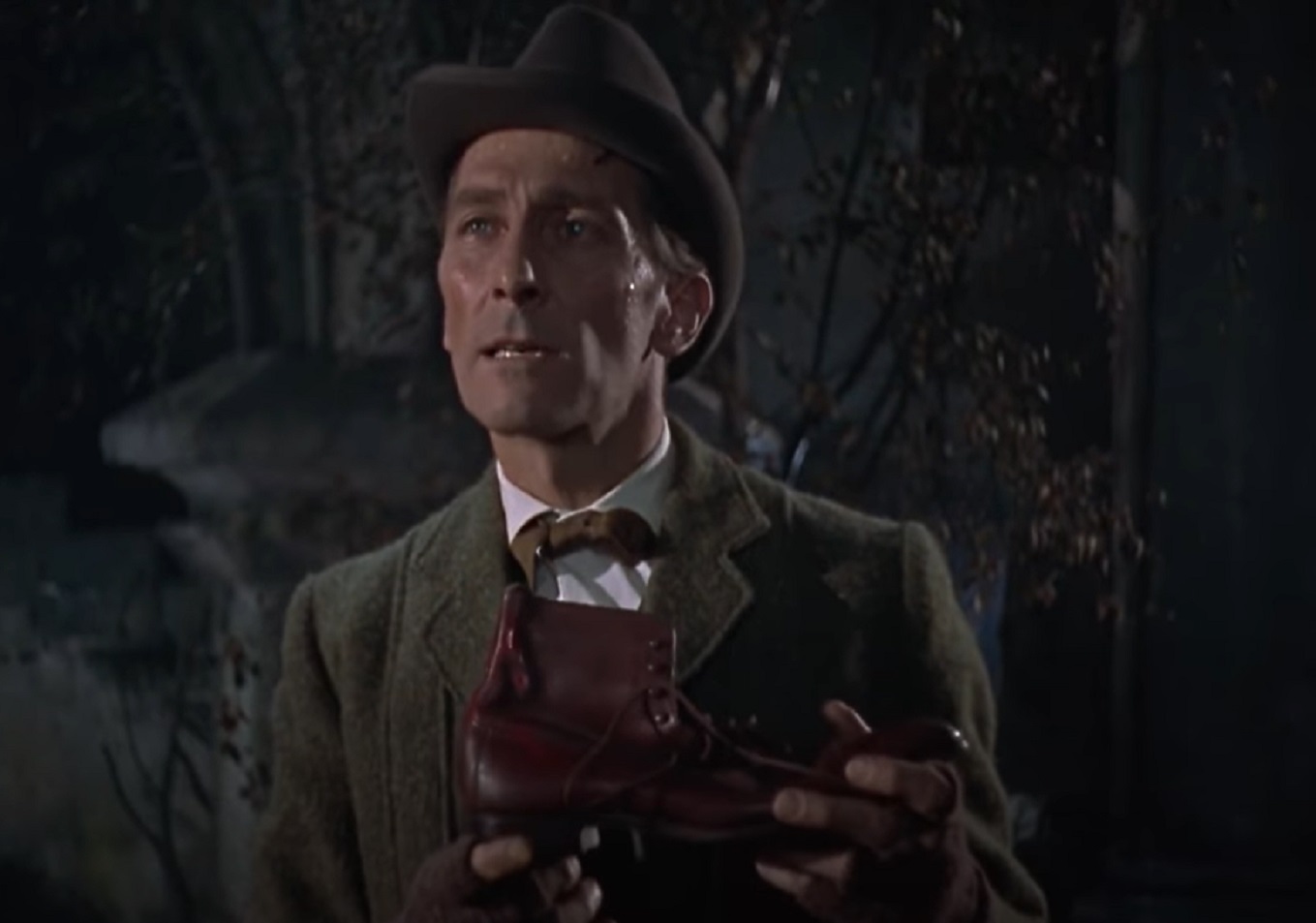 Screenshot of Peter Cushing wearing green coat and hat is looking outside - from The Hound of the Baskervilles (1959)